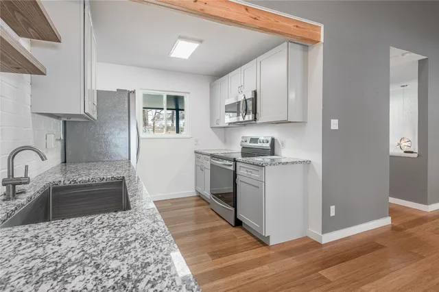 a kitchen with stainless steel appliances granite countertop a stove a sink and a refrigerator