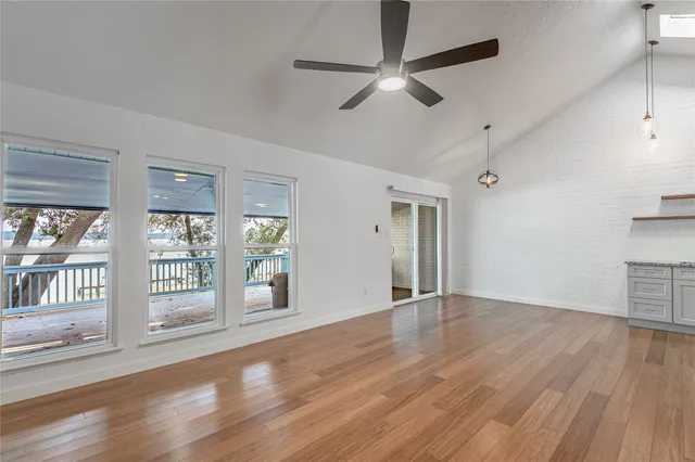 an empty room with wooden floor fan and windows