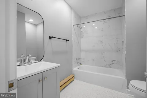 a bathroom with a bathtub shower sink vanity and toilet