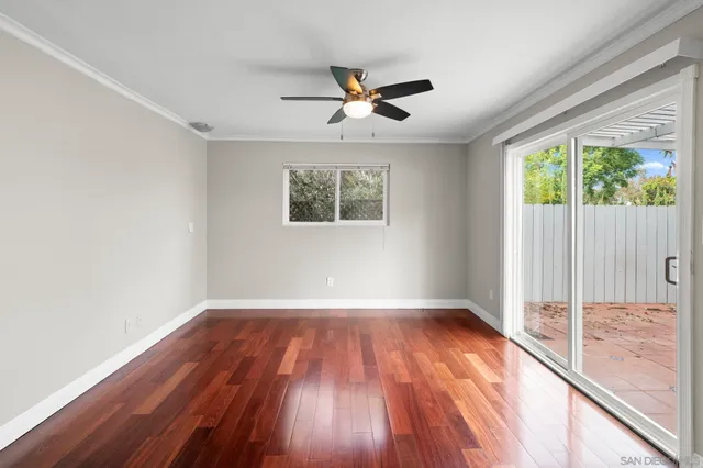 an empty room with wooden floor chandelier fan and windows
