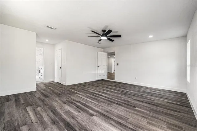 a view of empty room with wooden floor and ceiling fan