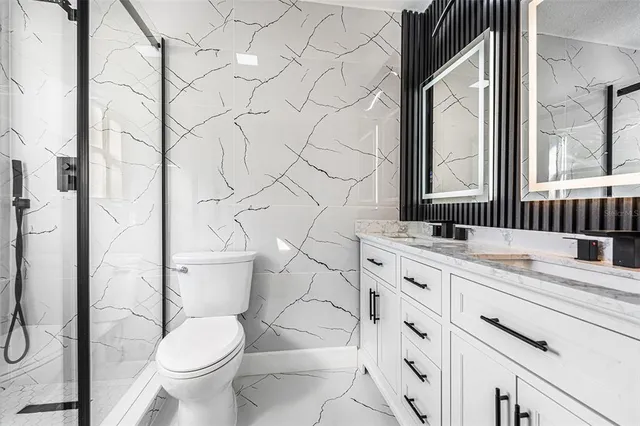a bathroom with a granite countertop toilet sink and mirror