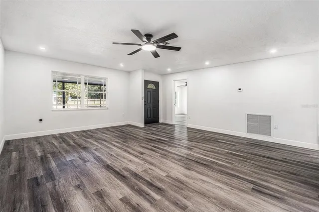 a view of an empty room with wooden floor and a window