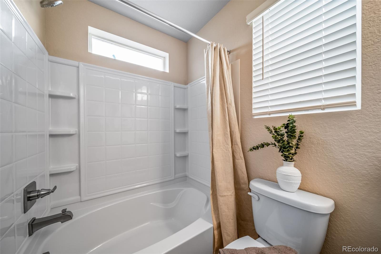 10155 Scranton Way Commerce City, CO 80022 - Photo 23 of 28 a bath room with a toilet and a bath tub