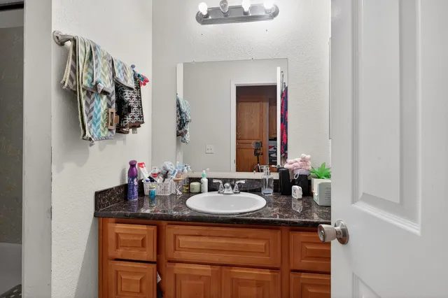 a bathroom with a granite countertop sink and a mirror