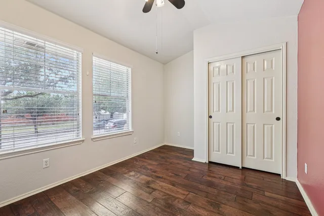 a view of an empty room with wooden floor and a window