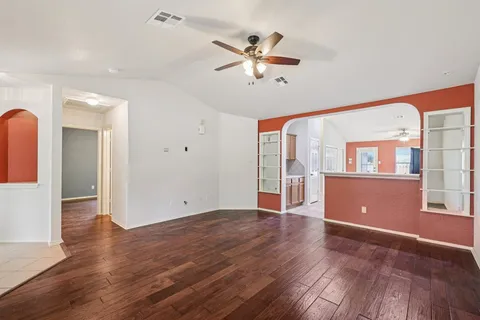 a view of an empty room with window and wooden floor