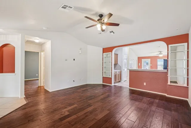 a view of an empty room with window and wooden floor