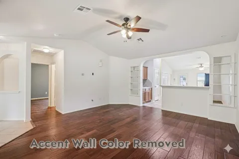 a view of an empty room with window and wooden floor
