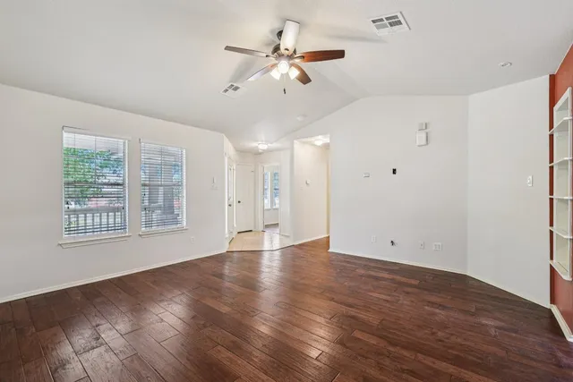 a view of an empty room with a window and wooden floor