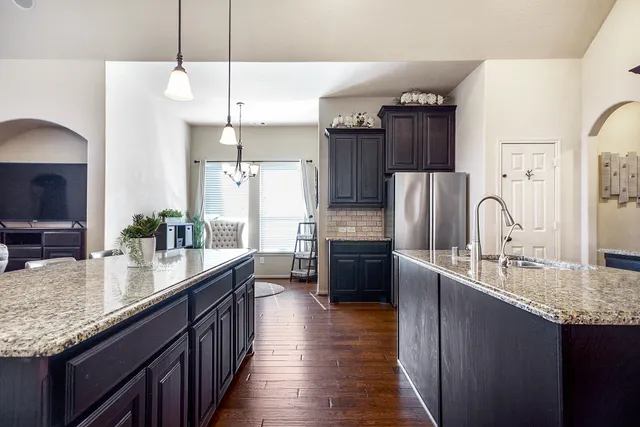 a large kitchen with stainless steel appliances granite countertop a stove a sink dishwasher and a refrigerator with wooden floor