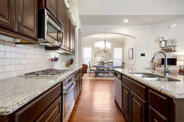a kitchen with stainless steel appliances kitchen island granite countertop a stove refrigerator and cabinets