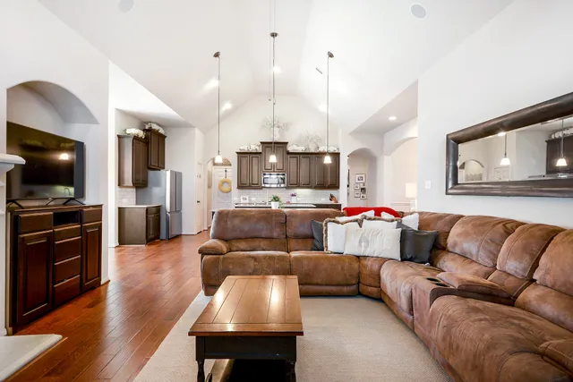 a living room with furniture kitchen area and a wooden floor