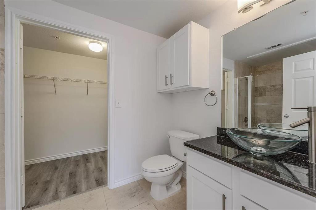 3102 Kings Road, Unit 2303 Dallas, TX 75219 - Photo 12 of 23 a bathroom with a granite countertop sink a toilet and a mirror