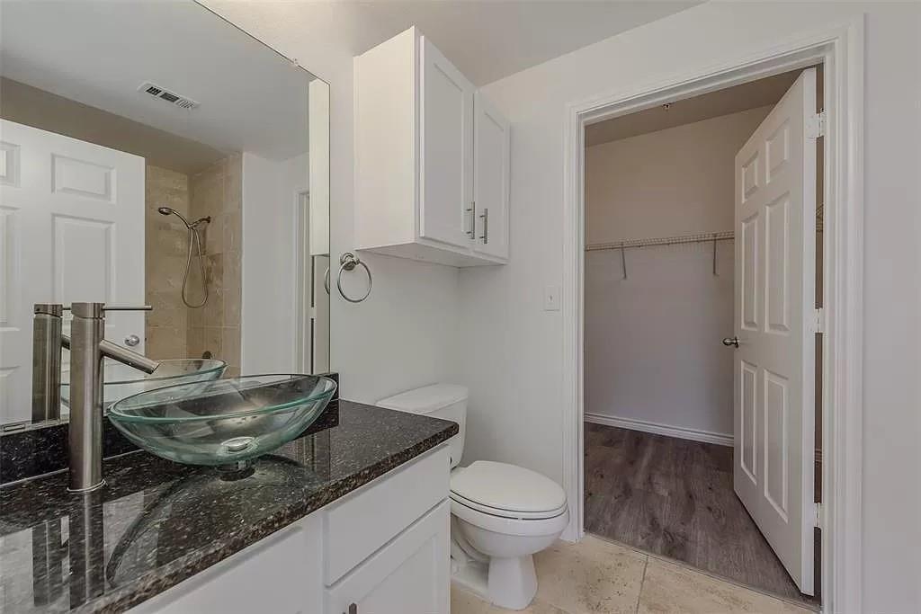 3102 Kings Road, Unit 2303 Dallas, TX 75219 - Photo 13 of 23 a bathroom with a granite countertop sink a toilet and a mirror