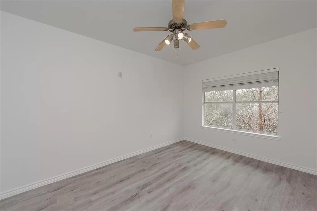 3102 Kings Road, Unit 2303 Dallas, TX 75219 - Photo 9 of 23 an empty room with wooden floor chandelier fan and window