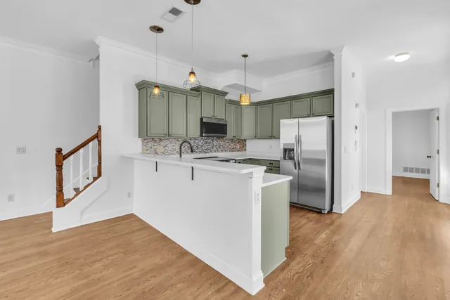 a kitchen with stainless steel appliances a refrigerator a sink cabinets and wooden floor