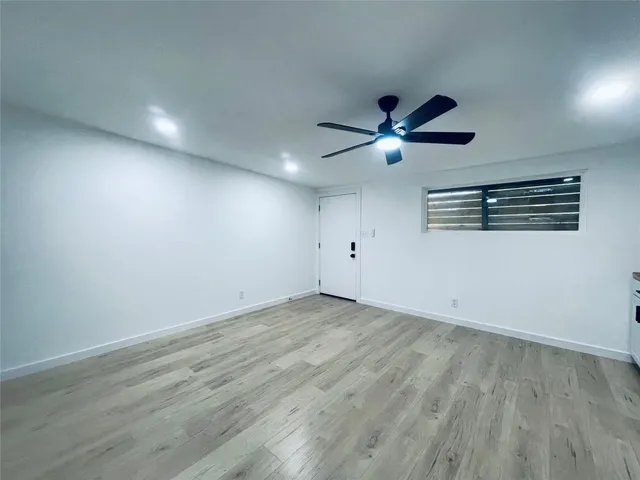 an empty room with wooden floor and ceiling fan