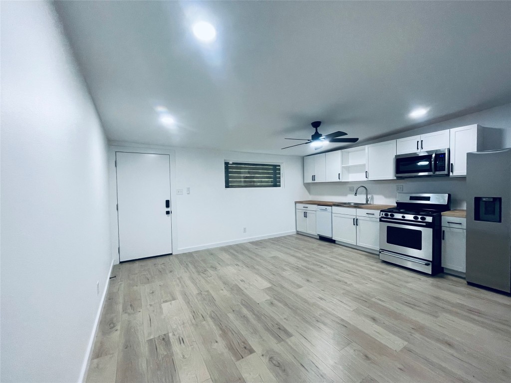 7107 Guadalupe Street, Unit 202 Austin, TX 78752 - Photo 5 of 8 Kitchen featuring appliances with stainless steel finishes, white cabinetry, light wood finished floors, a ceiling fan, and light countertops