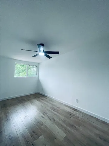an empty room with wooden floor chandelier fan and windows