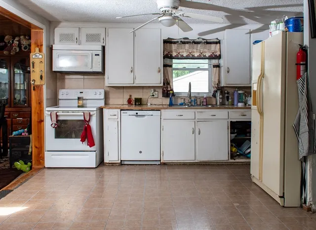 a kitchen with granite countertop a white stove top oven sink and cabinets