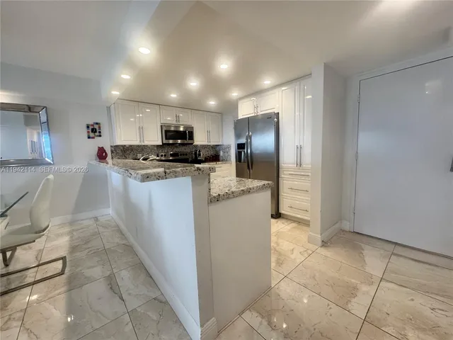 a kitchen with granite countertop a refrigerator and a stove top oven