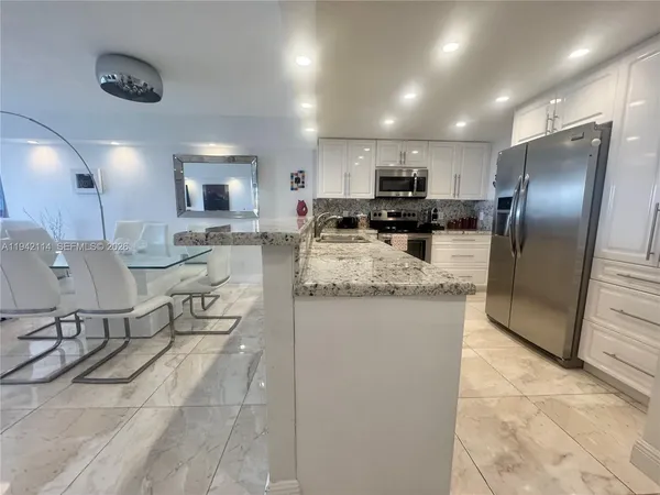 a kitchen with granite countertop a refrigerator and a sink