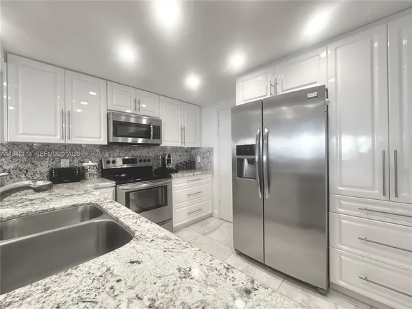 a kitchen with granite countertop a refrigerator and a sink