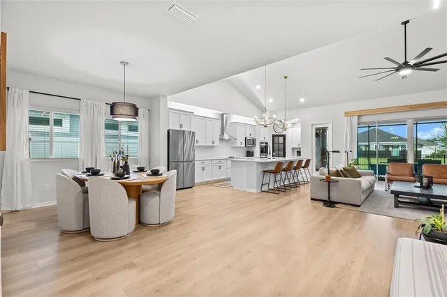 a very nice looking dining room with wooden floor and chandelier