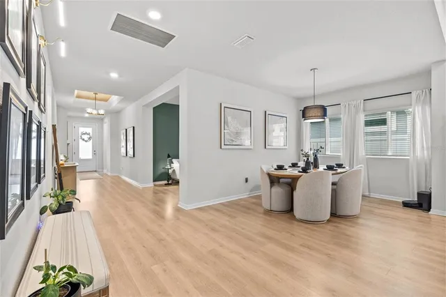 a kitchen with stainless steel appliances granite countertop a refrigerator a sink dishwasher a dining table and chairs with wooden floor