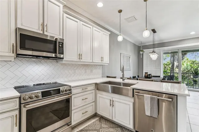 a kitchen with stainless steel appliances kitchen island granite countertop a dining table chairs and white cabinets