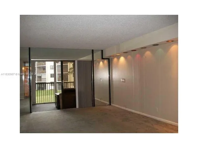 an empty room with chandelier fan and windows