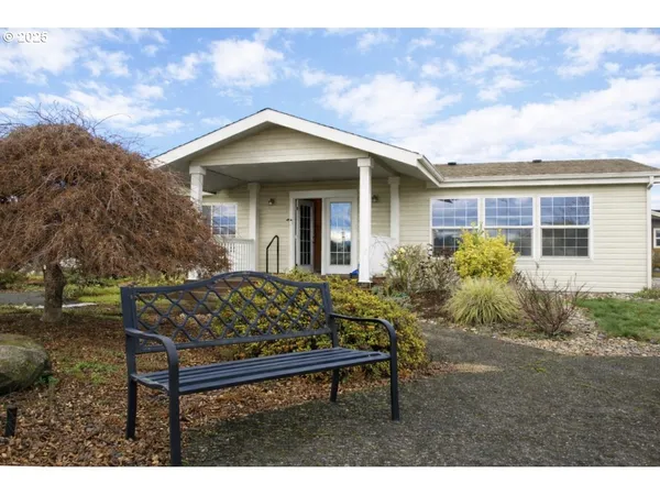 a view of a wooden house with a bench and plants