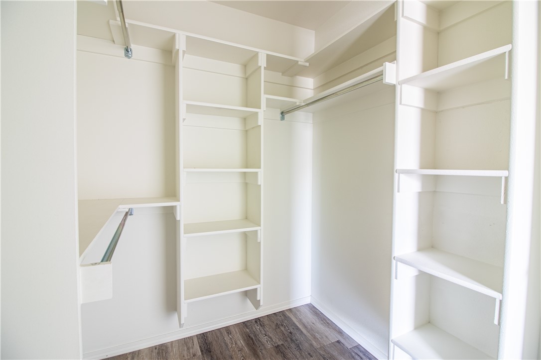 803 South Rupple Road, Unit 1 Fayetteville, AR 72704 - Photo 11 of 22 Spacious walk-in closet featuring multiple shelving units, integrated hanging rods, and wood-finish flooring