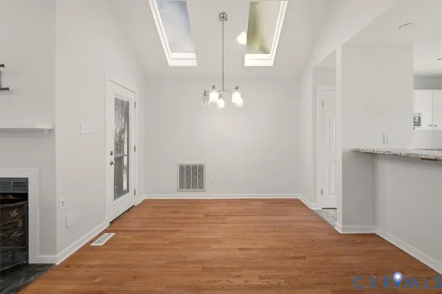 a view of a hallway with wooden floor and a kitchen