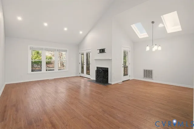 an empty room with wooden floor fireplace and windows