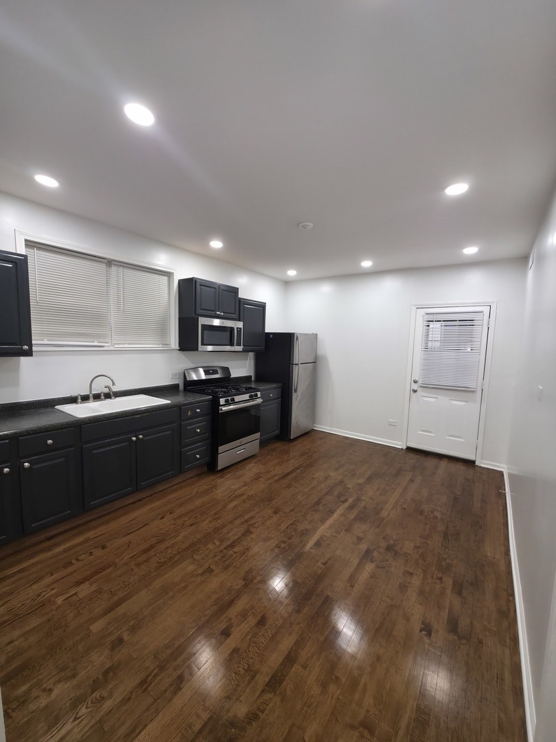 1748 North Keystone Avenue Chicago, IL 60639 - Photo 13 of 33 a large kitchen with kitchen island granite countertop a stove a sink and a microwave