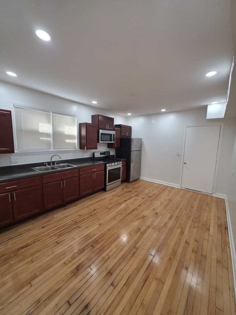 1748 North Keystone Avenue Chicago, IL 60639 - Photo 2 of 33 a large kitchen with wooden floors and stainless steel appliances