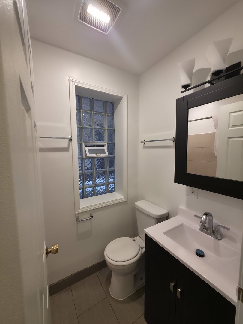 1748 North Keystone Avenue Chicago, IL 60639 - Photo 25 of 33 a bathroom with a toilet a sink a mirror and a window