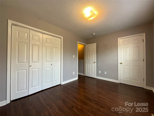 a view of an empty room with wooden floor & closet