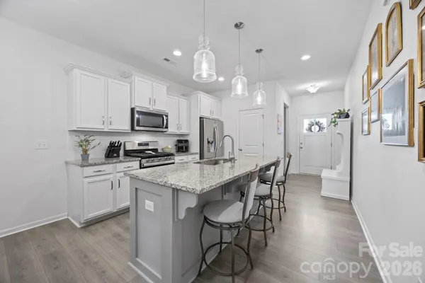 a kitchen with a dining table chairs wooden floor cabinets and stainless steel appliances