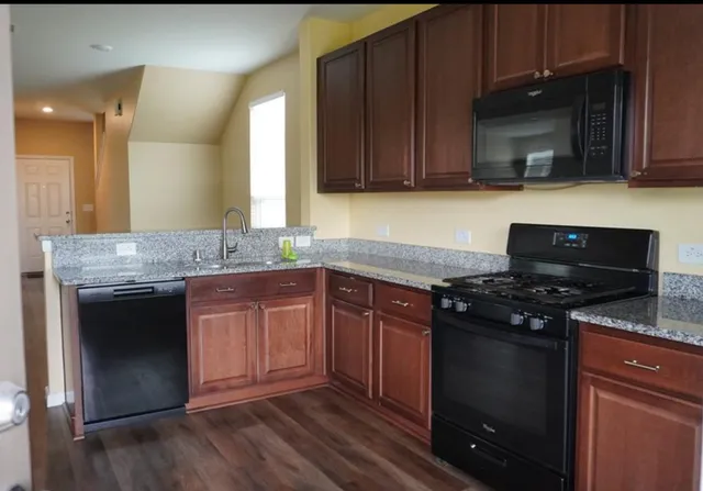 a kitchen with granite countertop stainless steel appliances a stove microwave and cabinets