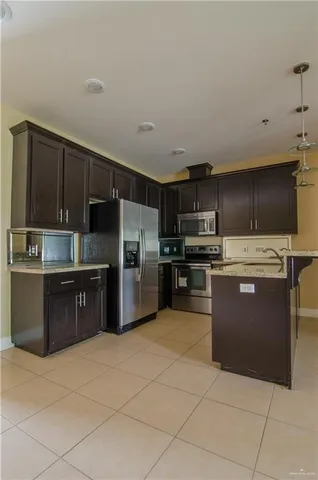 a large kitchen with a large counter top stainless steel appliances and cabinets