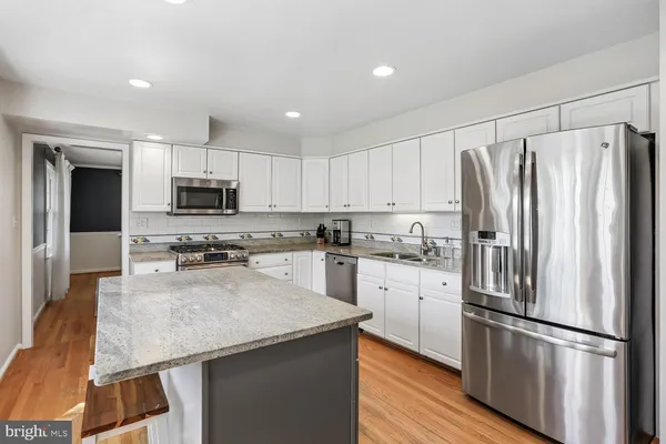 a kitchen with kitchen island granite countertop white cabinets and stainless steel appliances