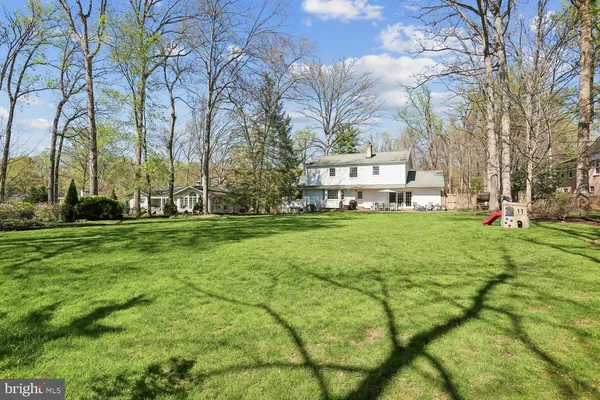 a view of a white house with a big yard and large trees