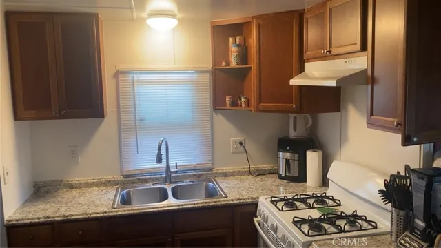 a kitchen with granite countertop a sink stove and cabinets