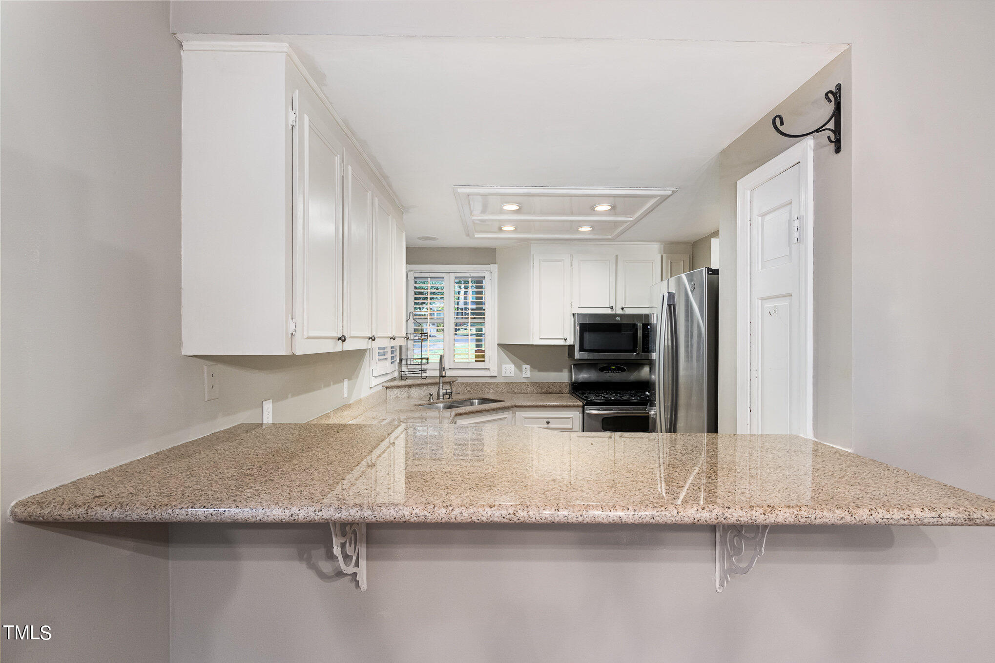 7831 Breckon Way Raleigh, NC 27615 - Photo 9 of 29 a kitchen with granite countertop a sink and a stove top oven with wooden floor