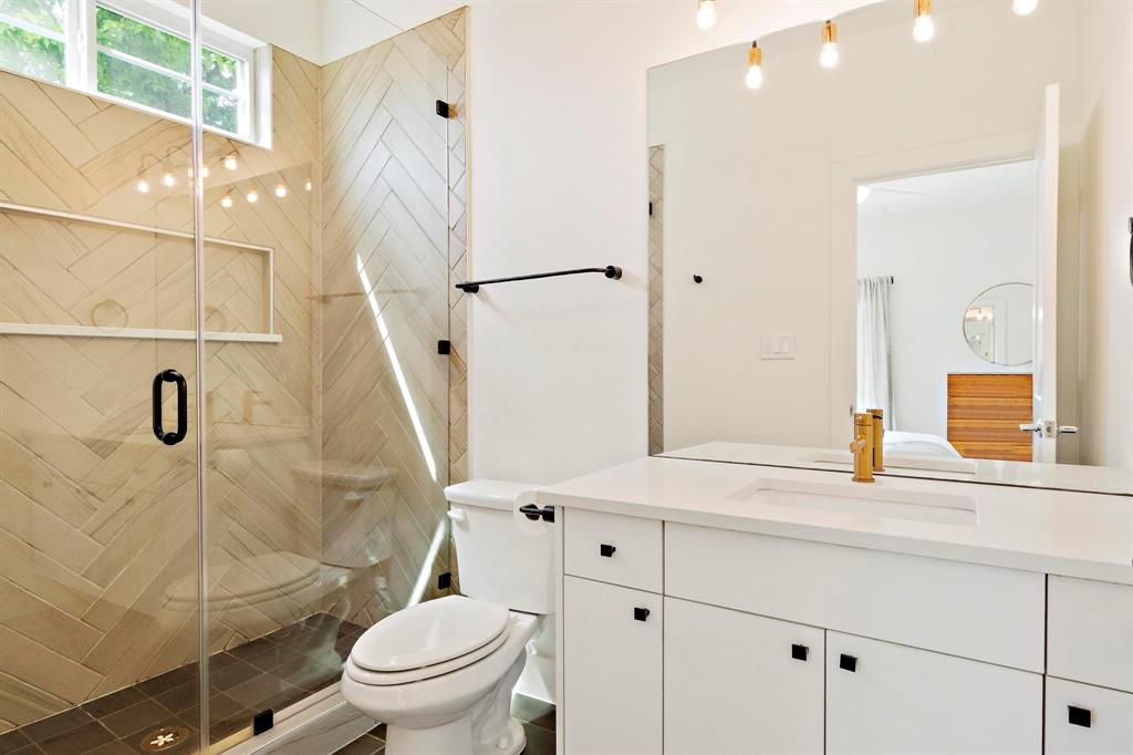 911 Stobaugh Street, Unit 2 Austin, TX 78757 - Photo 17 of 26 Full bathroom featuring a glass-enclosed shower with herringbone tile and integrated shelving