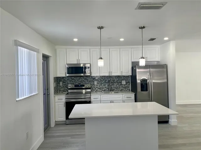 a kitchen with kitchen island white cabinets and stainless steel appliances