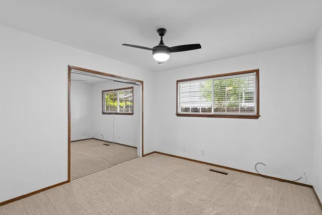an empty room with a window and a ceiling fan